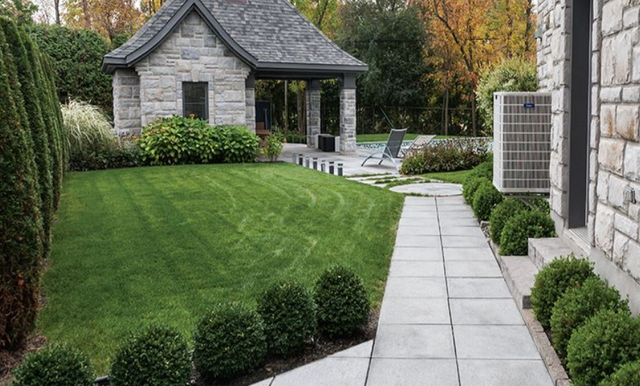 Outdoor patio area with flagstone pavers, furniture, and a view of a body of water and rocks in the background.
